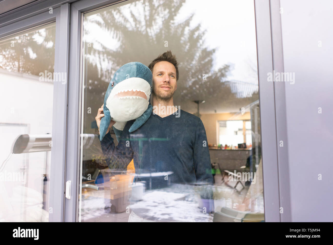 L'homme à la fenêtre, de l'exécution toy requin sur son épaule Banque D'Images