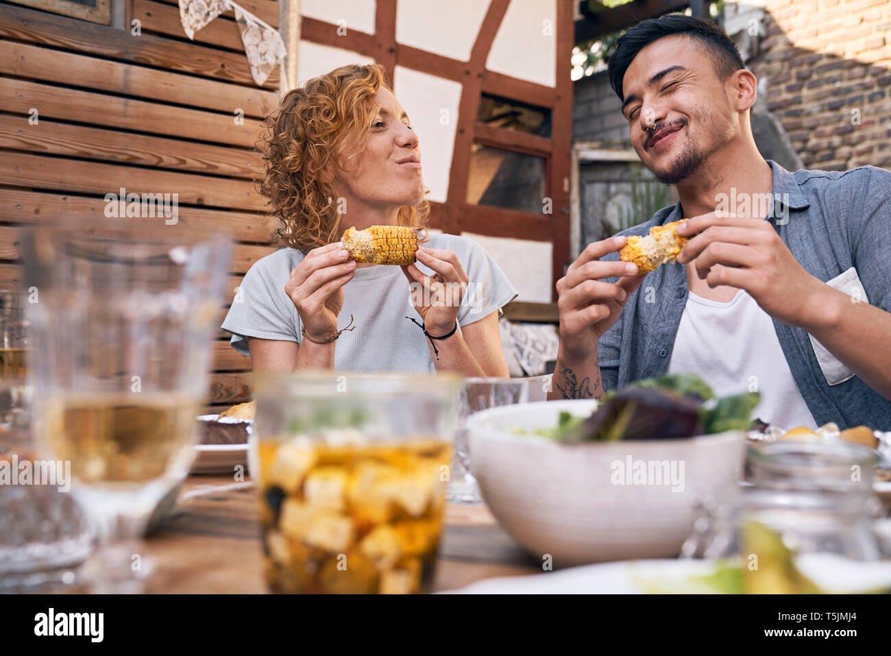 Couple de manger des épis de maïs grillés au barbecue dans la cour arrière Banque D'Images