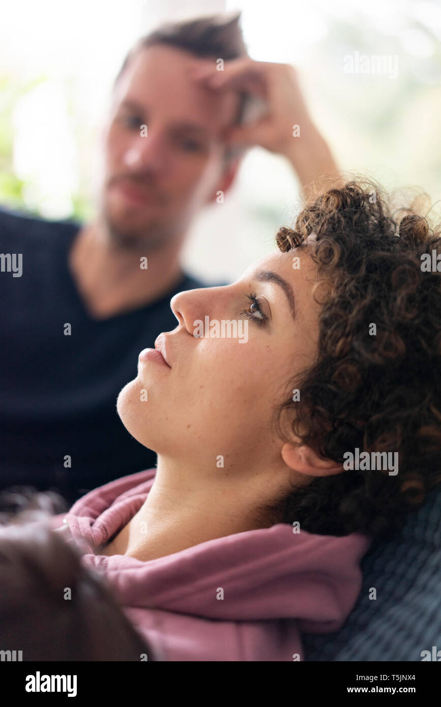 Homme qui regarde sa femme se détendre sur le canapé Banque D'Images