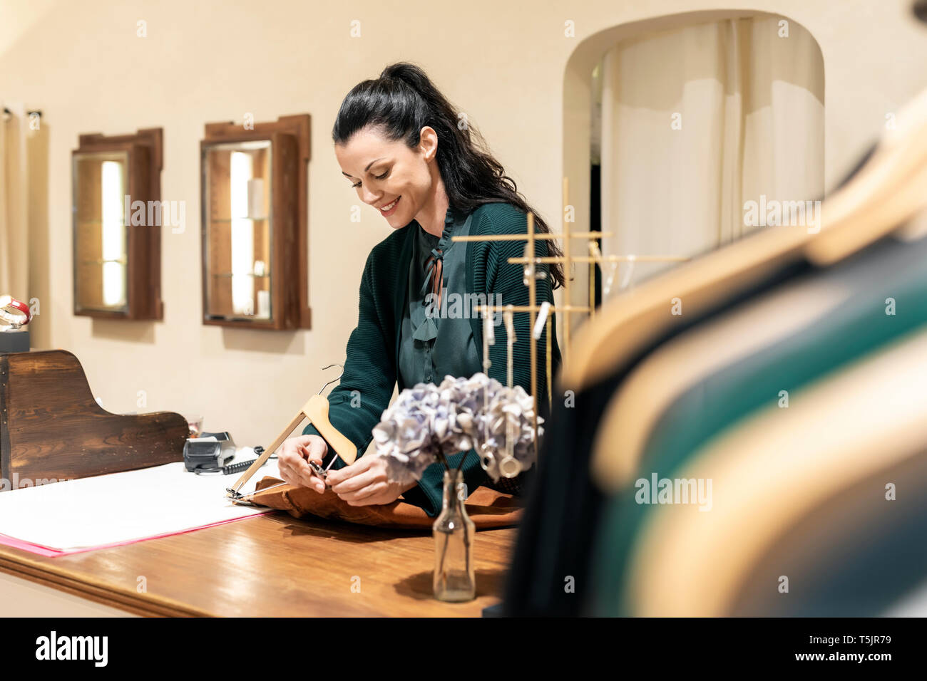 Mature Woman working in fashion store, fixation des vêtements sur cintres Banque D'Images