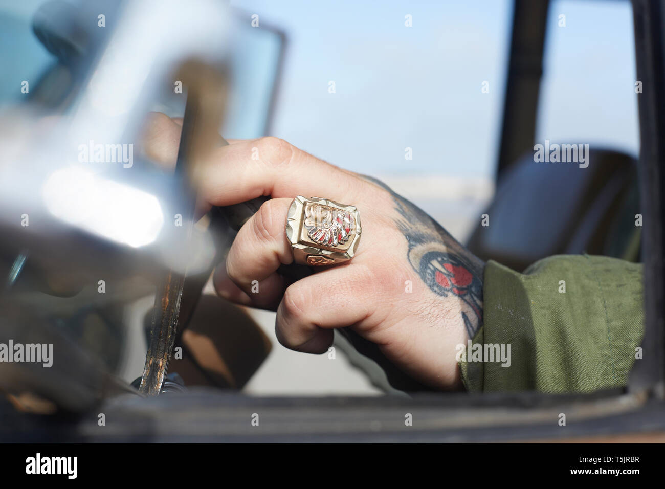 La main de l'homme avec l'anneau et le tatouage au volant de voiture Banque D'Images