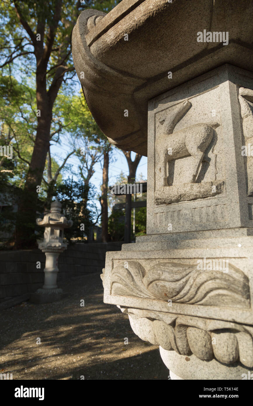 Une lanterne - pierre décorée d'une figure de cheval se trouve dans la masse boisée à Maginu e culte, Kawasaki, Japon. Banque D'Images