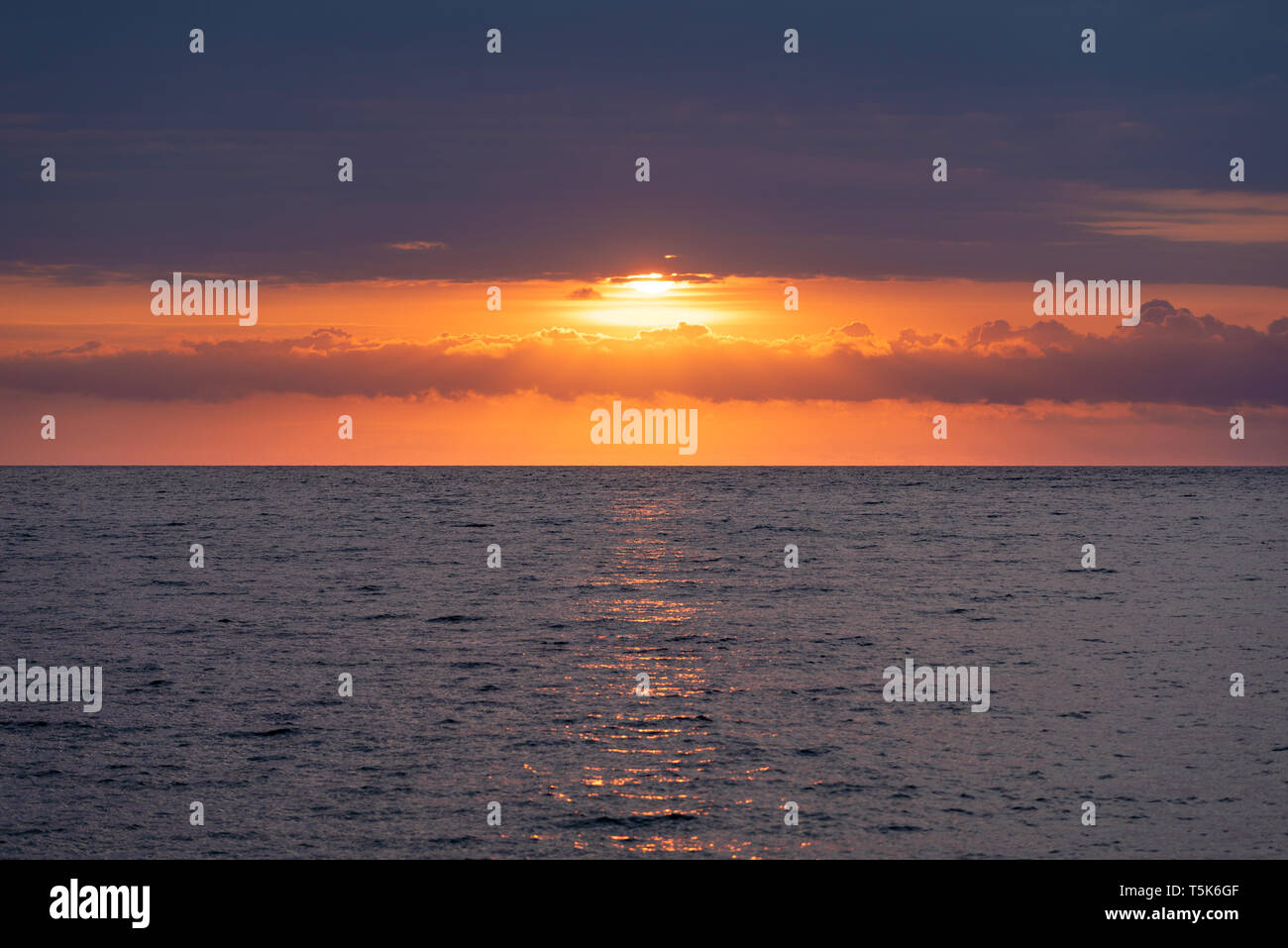 Marin avec un beau lever de soleil. Le soleil est caché derrière de beaux nuages Banque D'Images