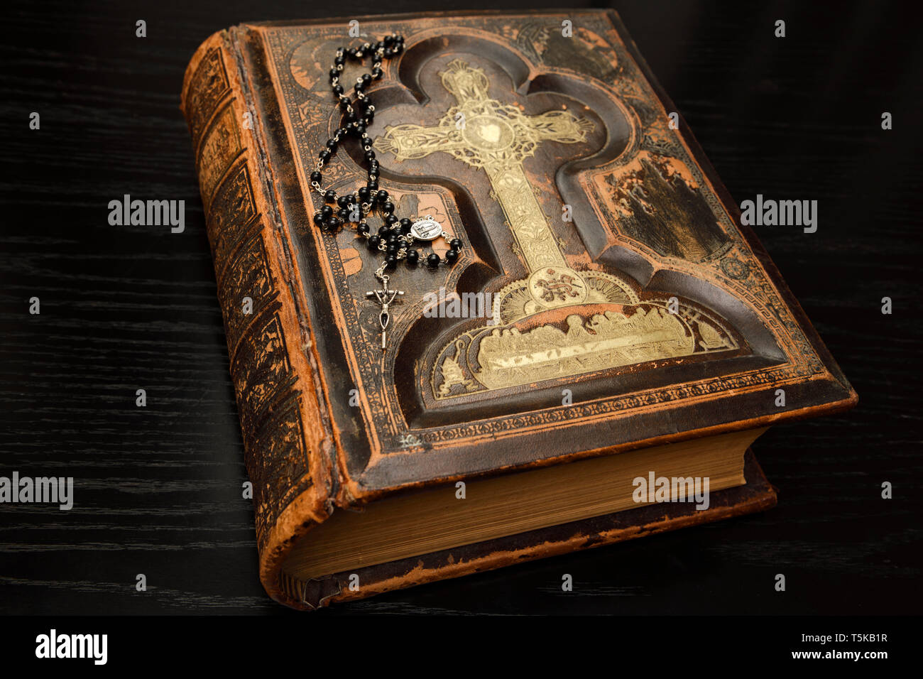 Sainte Bible relié en cuir antique avec chapelet sur table en chêne noir Banque D'Images