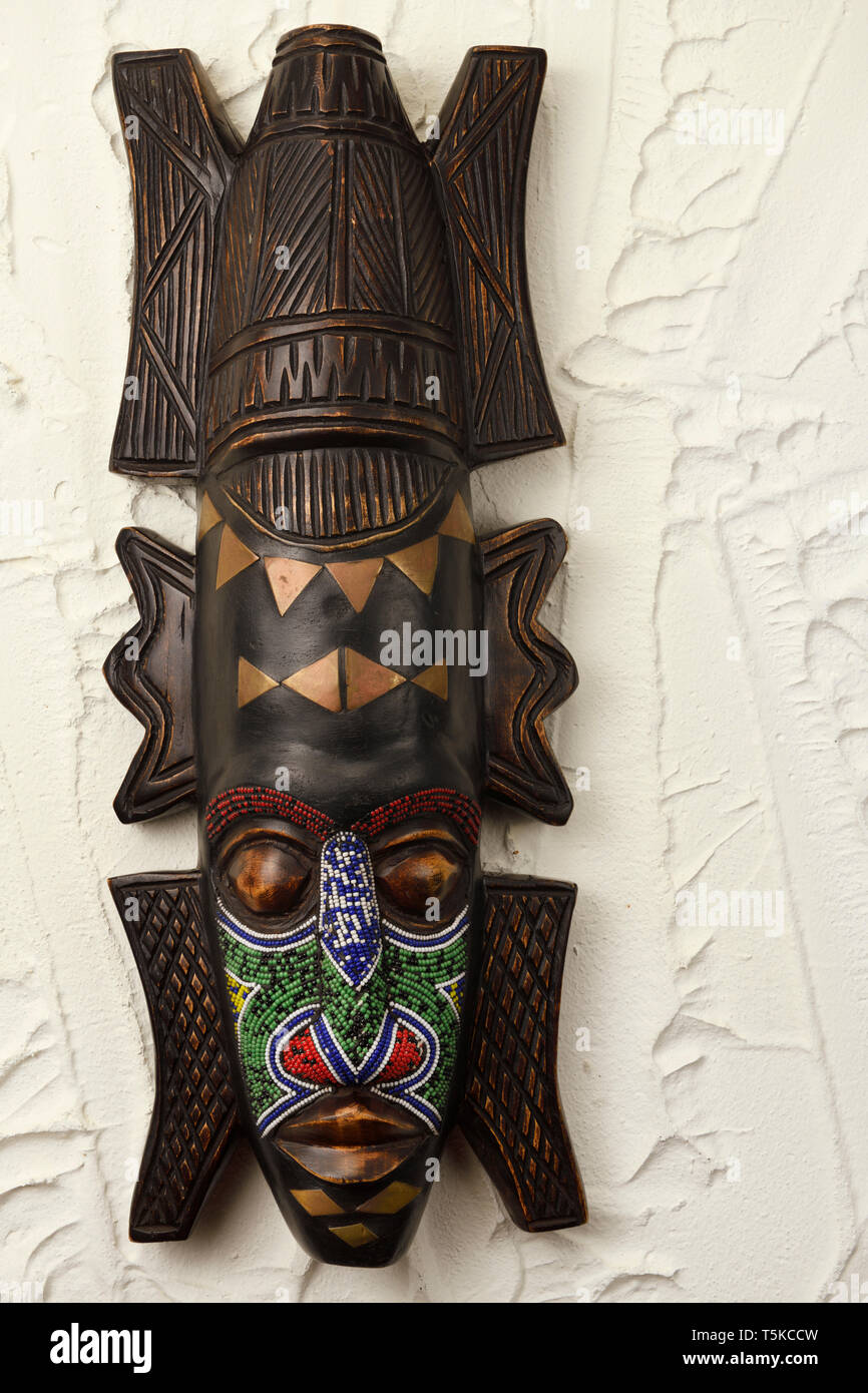 Masque de cérémonie en bois sculpté d'Ashanti du Ghana de perles et de laiton sur mur en stuc Banque D'Images
