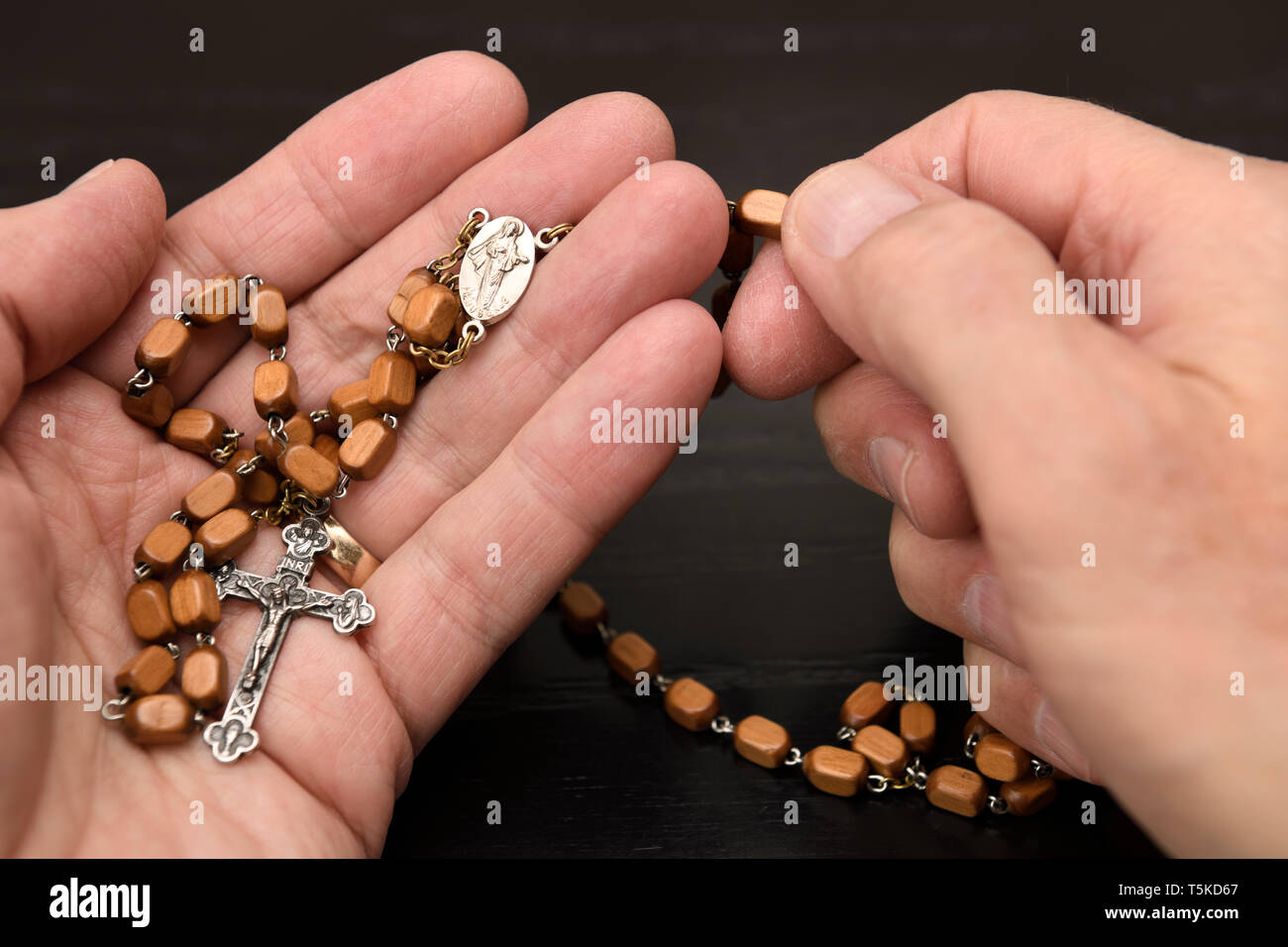 Mains de vieil homme tenant un chapelet de Medjugorje et méditant et priant le crucifix avec perles de bois Banque D'Images
