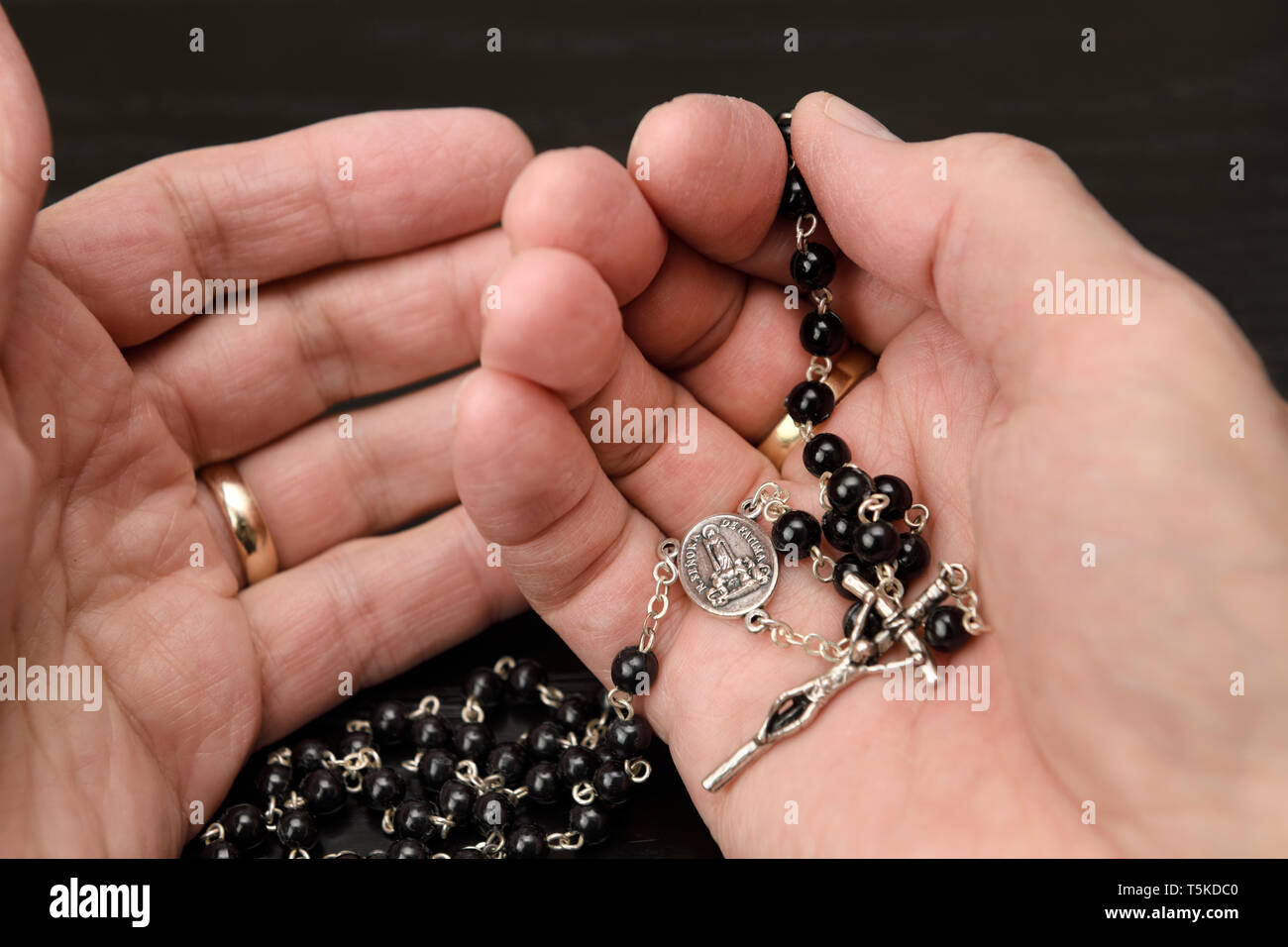 Les mains de l'homme de prier le Rosaire avec perles et crucifix avec Marie Notre Dame de Fatima Banque D'Images