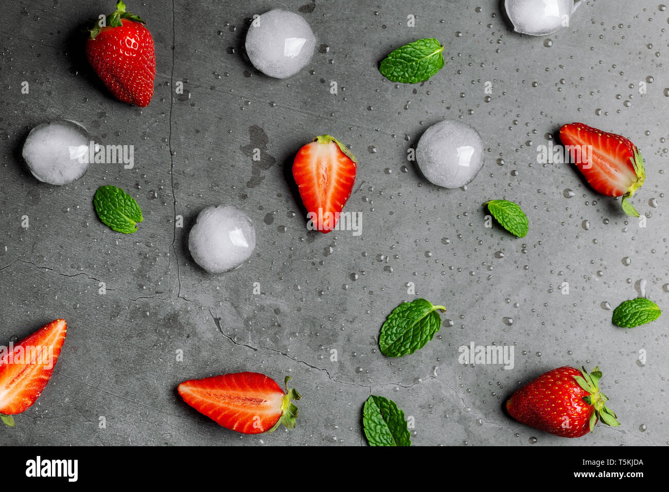Les fraises, les cubes de glace et de feuilles de menthe sur du marbre noir Banque D'Images