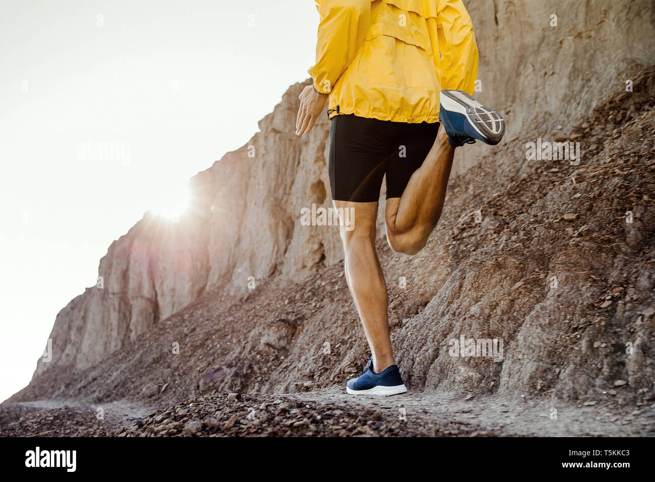 Retour homme runner s'exécutant sur sentier de montagne au coucher du soleil Banque D'Images