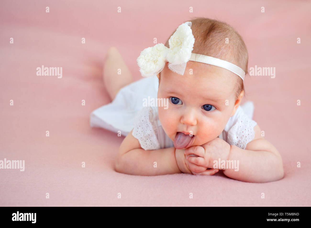 Portrait Of A Cute Naissance Bebe Fille En Robe Blanche Et Bandeau Couchee Sur Le Ventre Dans La Chambre Sur La Douce Couverture Rose Photo Stock Alamy