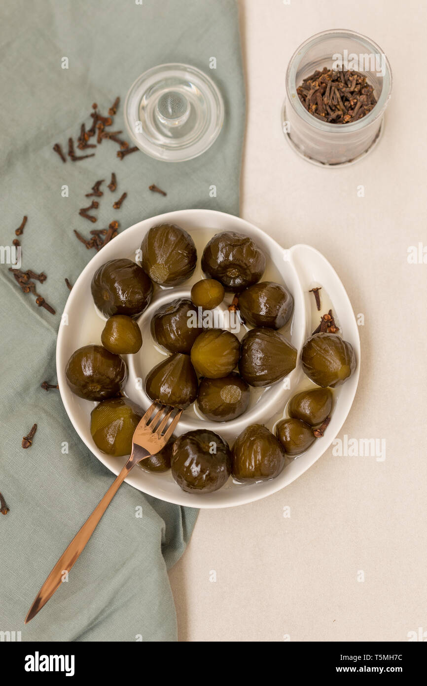 Vue supérieure tourné de confiture de figues en blanc plaque en céramique cuite avec des clous de girofle. Composition verticale. Banque D'Images