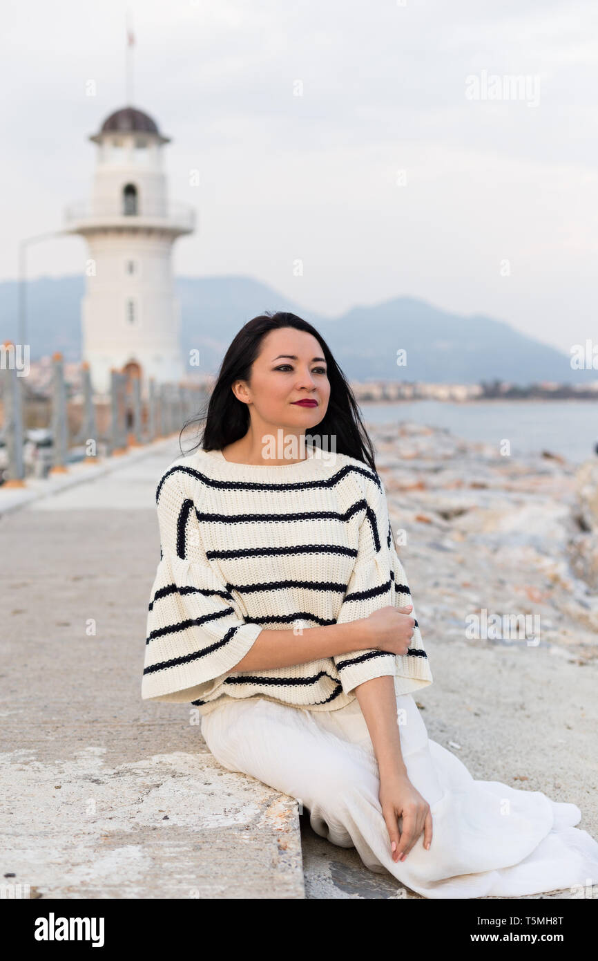 Femme romantique dans un style marin, vêtements assis près du phare.  Composition verticale Photo Stock - Alamy