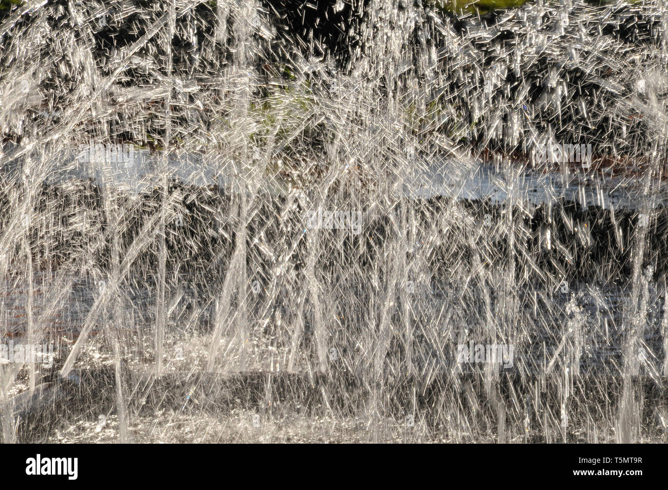 Un gros plan sur rétroéclairé de la pulvérisation des jets d'eau qui se croisent dans une fontaine. Banque D'Images