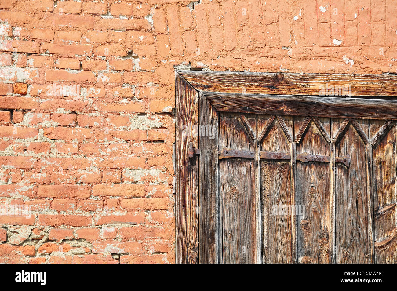 Façade en briques d'une ancienne grange avec porte en bois et fer à repasser agencement Banque D'Images