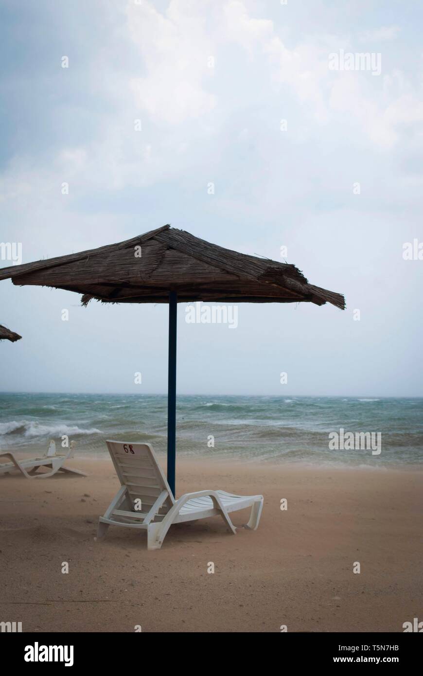 Tempête sur la mer avec des nuages orageux. Parasol et transats inversée  sous parasol sur la plage Photo Stock - Alamy