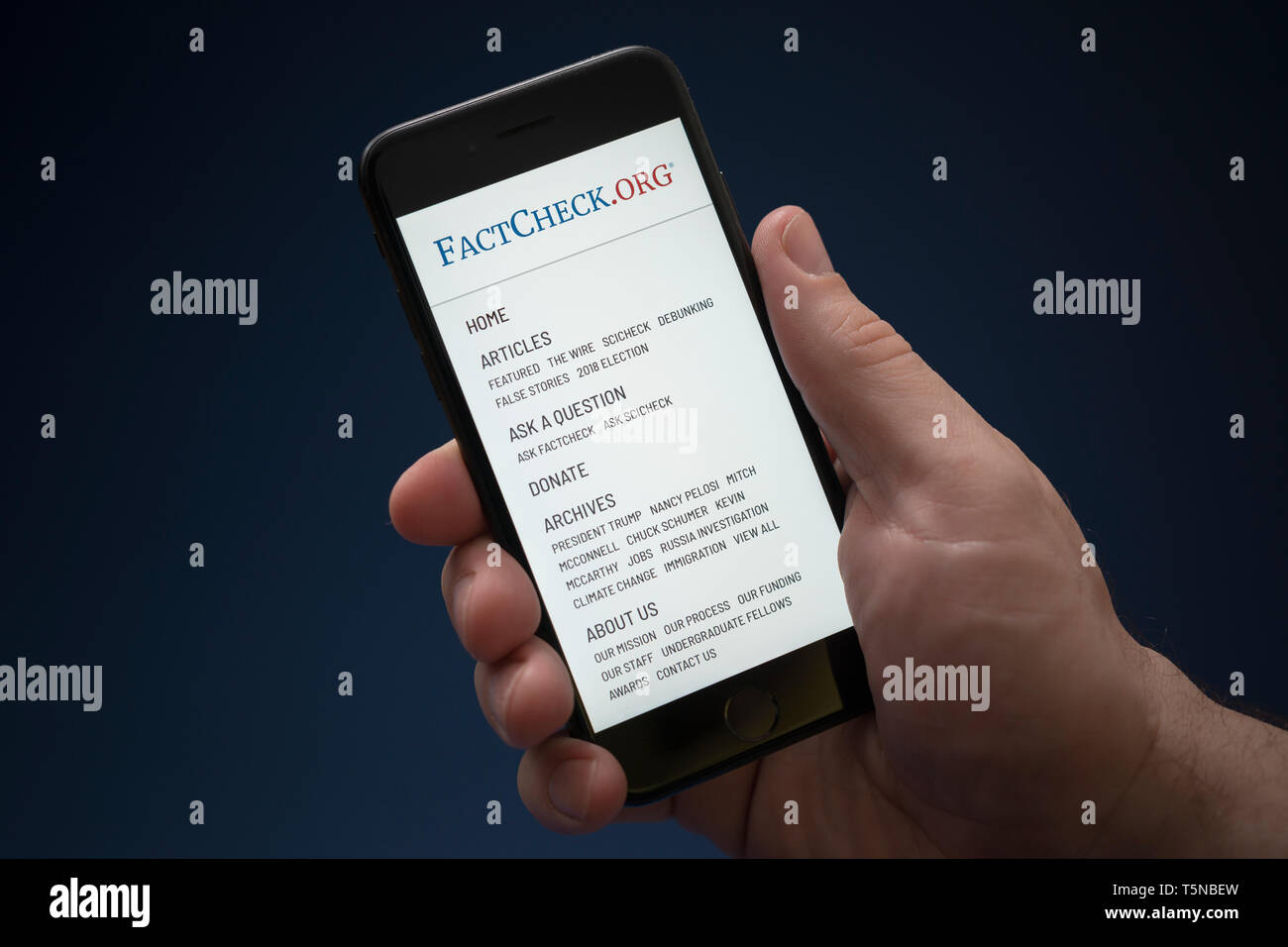 Un homme se penche sur son iPhone qui affiche le logo fait contrôler (usage éditorial uniquement). Banque D'Images