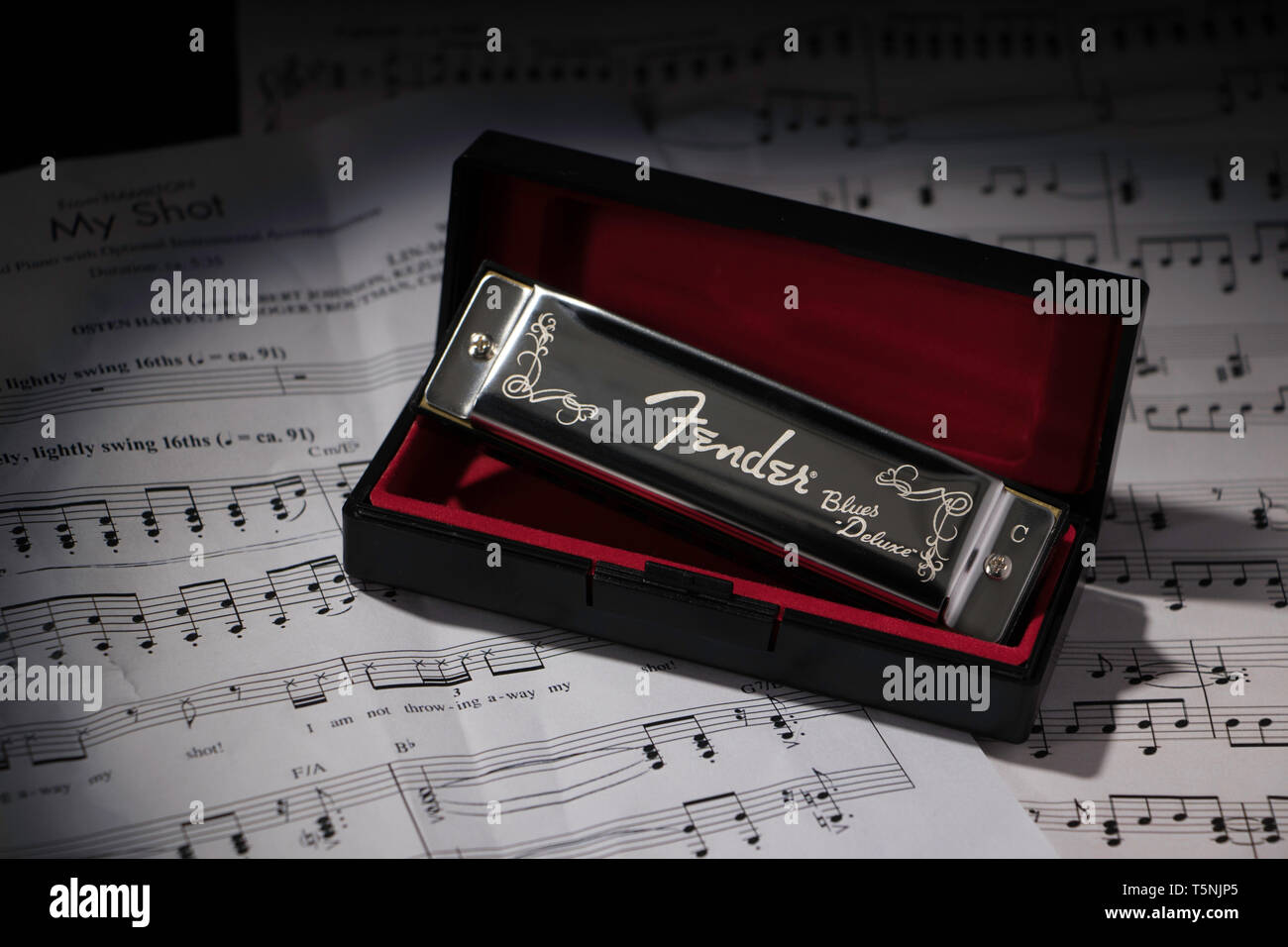 Une Fender harmonica dans une boîte doublée de velours rouge, assis sur une feuille pliée music Banque D'Images