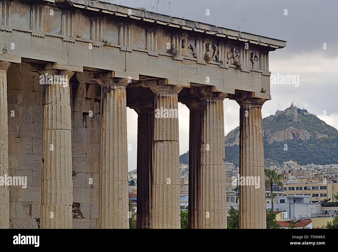 Détail du temple d'Héphaïstos à Athènes, Grèce. La colline du Lycabette et bâtiment de ville en arrière-plan. Banque D'Images