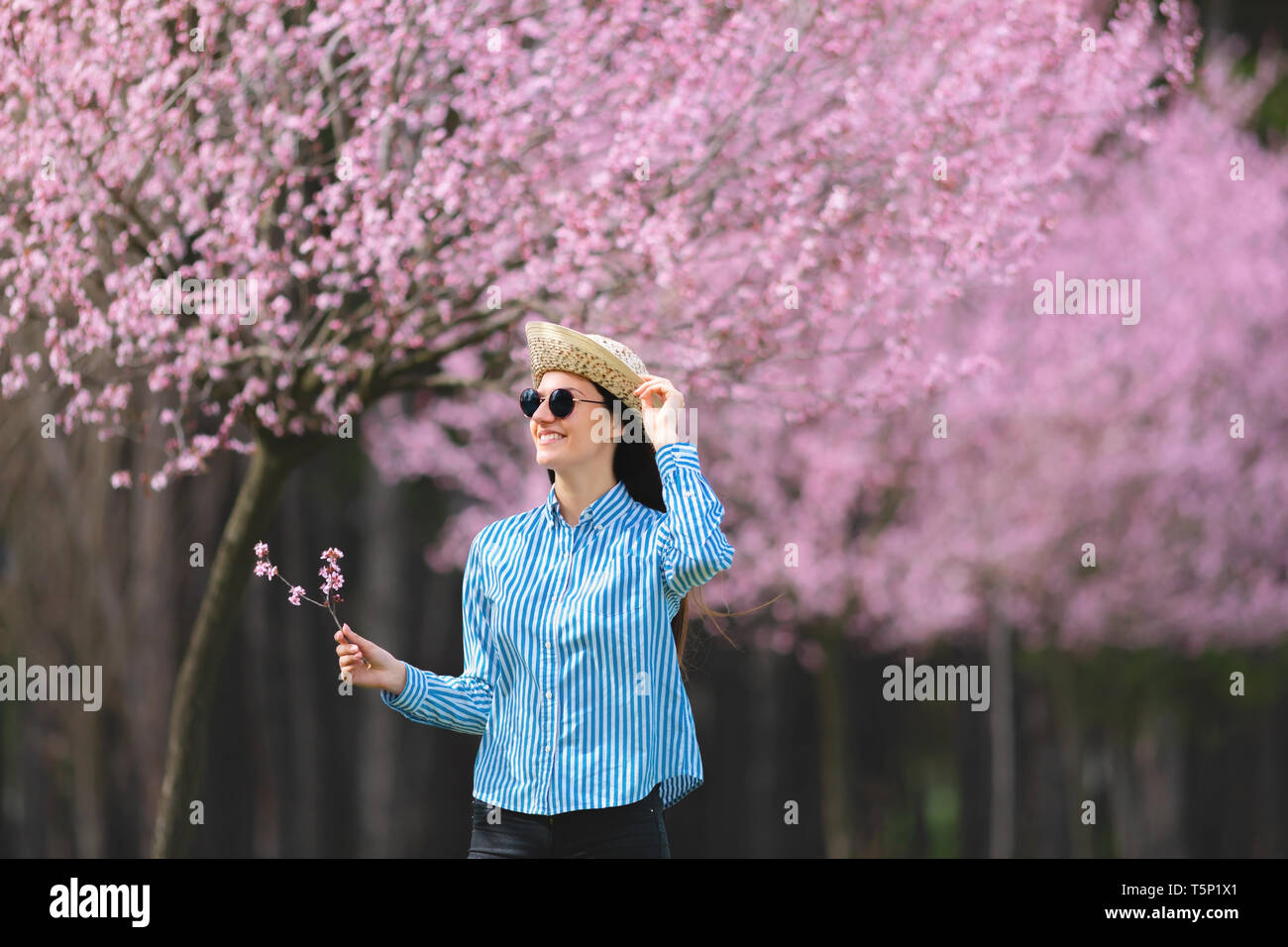 Belle jeune femme dans les fleurs de cerisier en fleurs jardin Banque D'Images