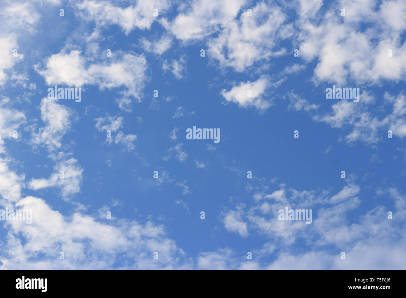 Image d'un ciel avec de petits nuages blancs dispersés dans le ciel et un espace vide au milieu de l'image pour placer du texte. Banque D'Images