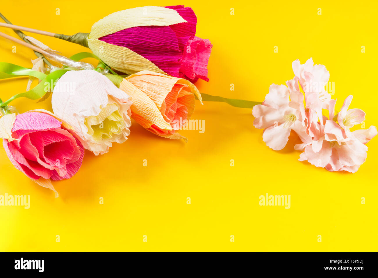 Des fleurs en papier ondulé sur fond jaune Banque D'Images