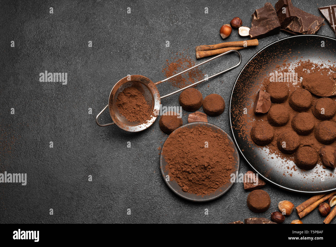Truffes au chocolat bonbons et poudre de cacao foncé sur fond de béton Banque D'Images