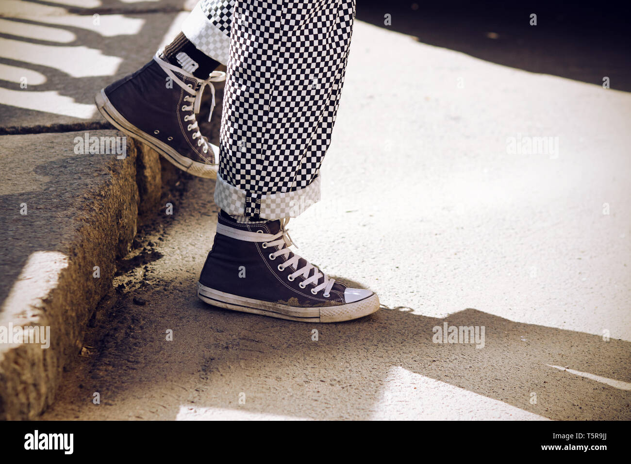 Jambes vêtues de pantalons à carreaux rétro à la mode, roulé jusqu'en bas,  et en bleu chaussures de descendre de l'étape, éclairé par la lumière du  soleil Photo Stock - Alamy