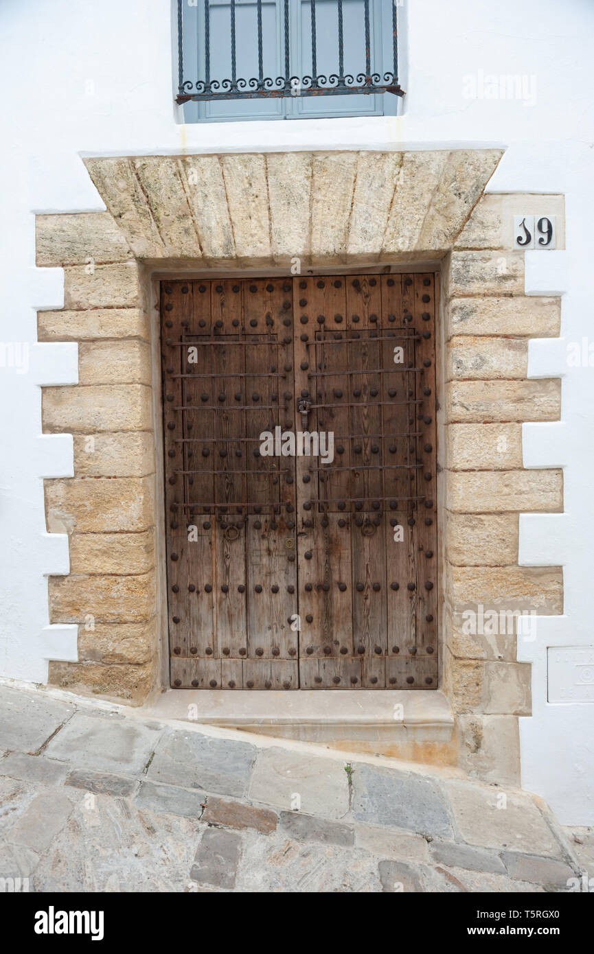 En bois marron avec porte cloutée en surround en pierre mur peint en blanc Banque D'Images