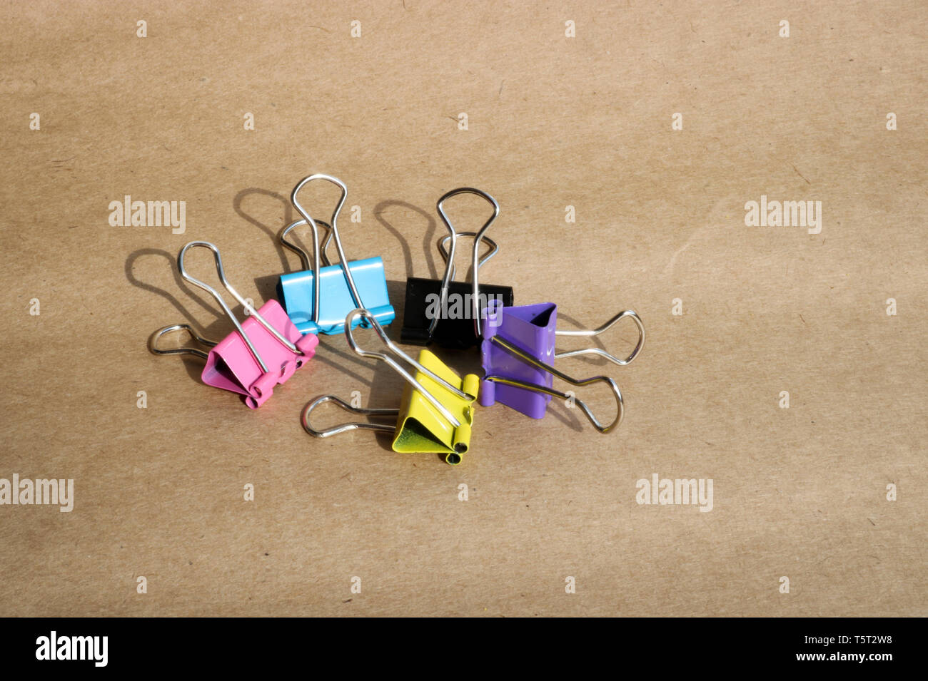 Clips pour papier de différentes couleurs sur le fond de papier kraft brun. La papeterie. Avec l'exemplaire de l'espace pour le texte. Banque D'Images