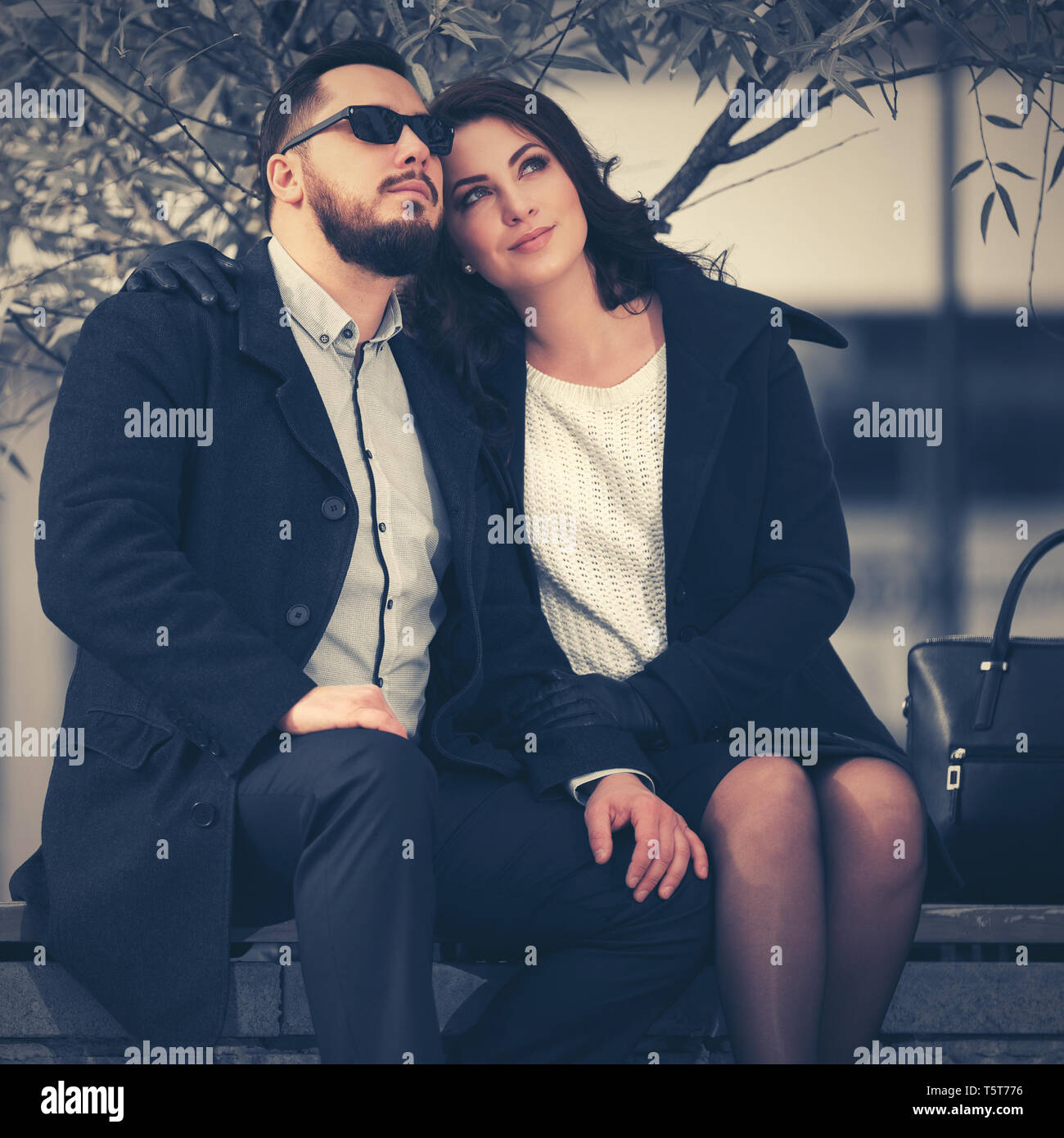 Heureux mode jeune couple amoureux assis sur un banc a la mode elegant l homme et de la femme en couches noir classique Photo Stock Alamy