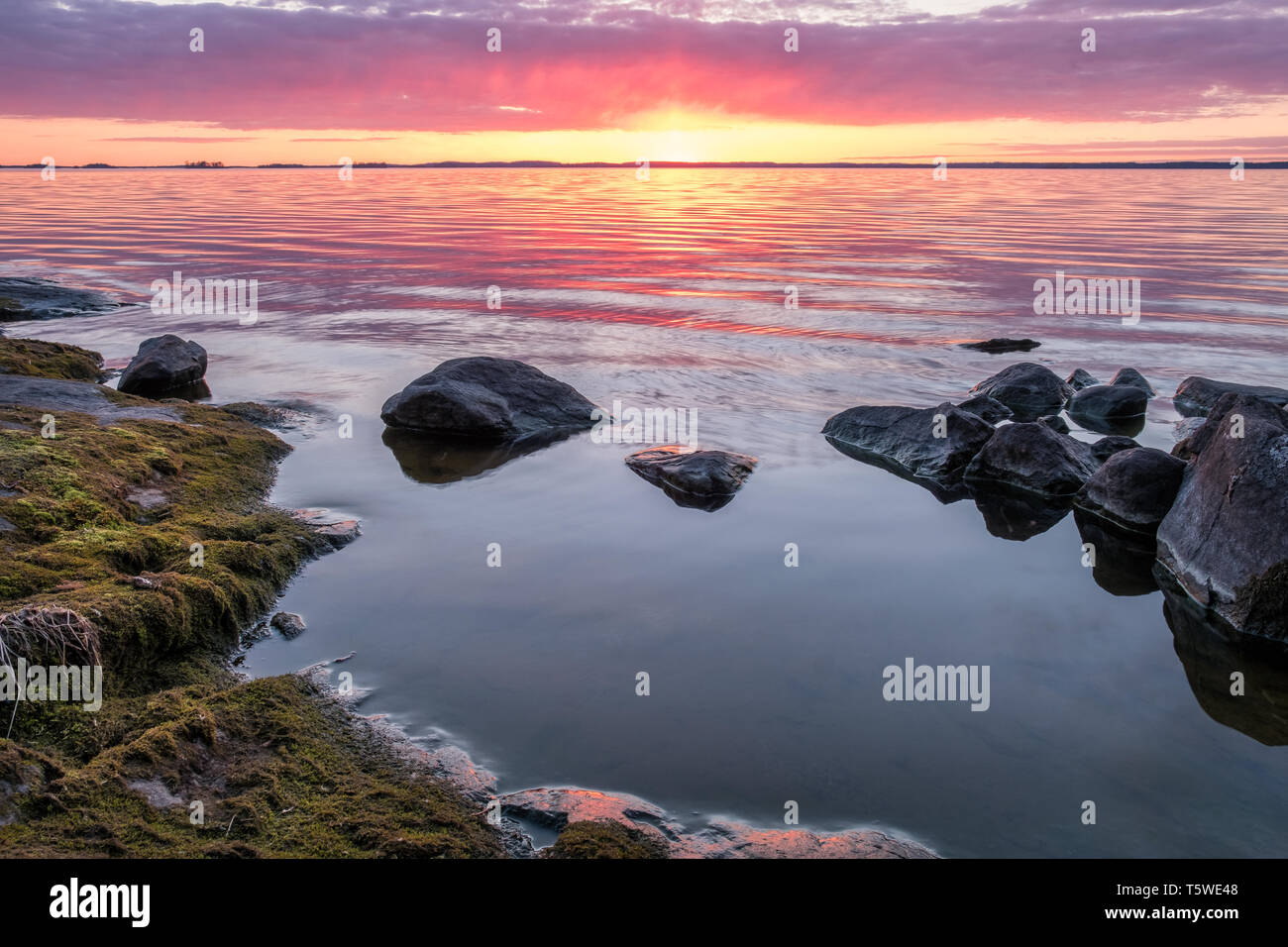Coucher du soleil avec vue panoramique lac paisible et roche à la soirée de printemps en Finlande Banque D'Images