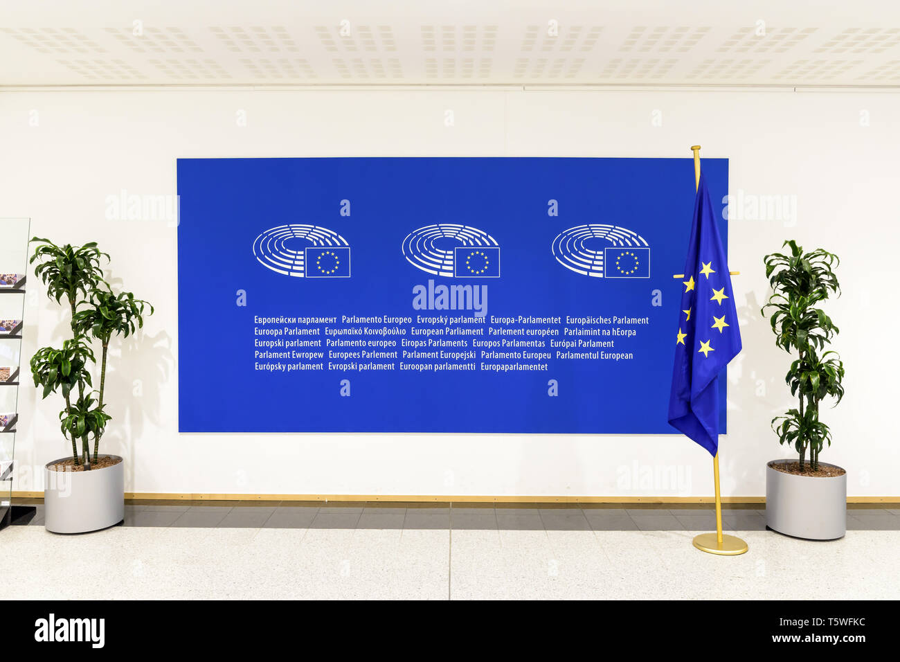 Vue de face d'un grand panneau bleu avec le logo et le nom du Parlement européen sur le mur avec un drapeau de l'Union européenne. Banque D'Images