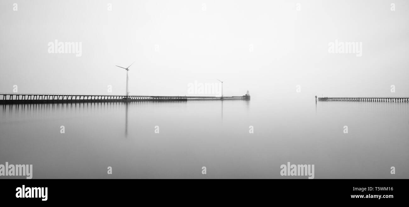 Pas de lever de soleil sur ce matin à Blyth Piers, mais le littoral était entouré par un épais brouillard qui fait pour certains à l'atmosphère B&W sur les éoliennes Banque D'Images