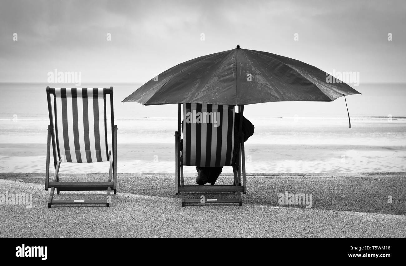 Pas de lever ce matin à Blyth cabines de plage, le littoral était entouré de brouillard et de la pluie, cela n'a pas empêché les habitants avec leurs chaises longues et parasol Banque D'Images