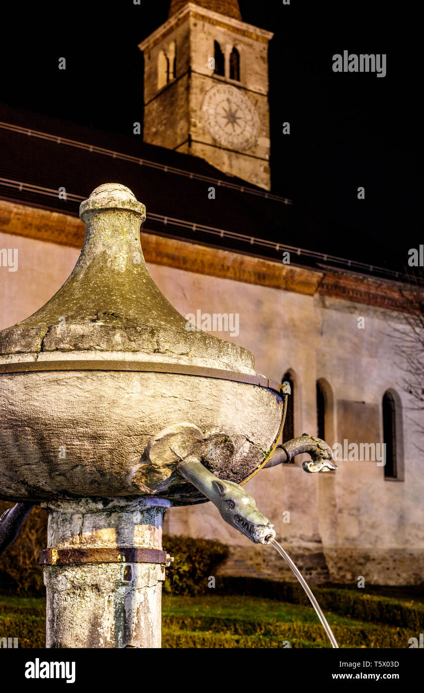 Belle vue sur fontaine en face d'une église avec une horloge dans un village italien de nuit Banque D'Images