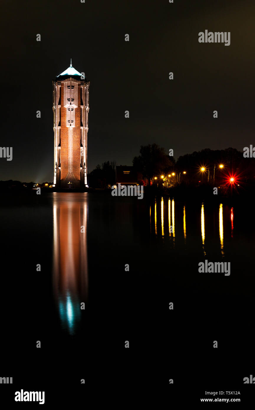 La tour phare à côté d'un immense lac de nuit avec des lanternes de la rue et de reflet dans l'eau Banque D'Images