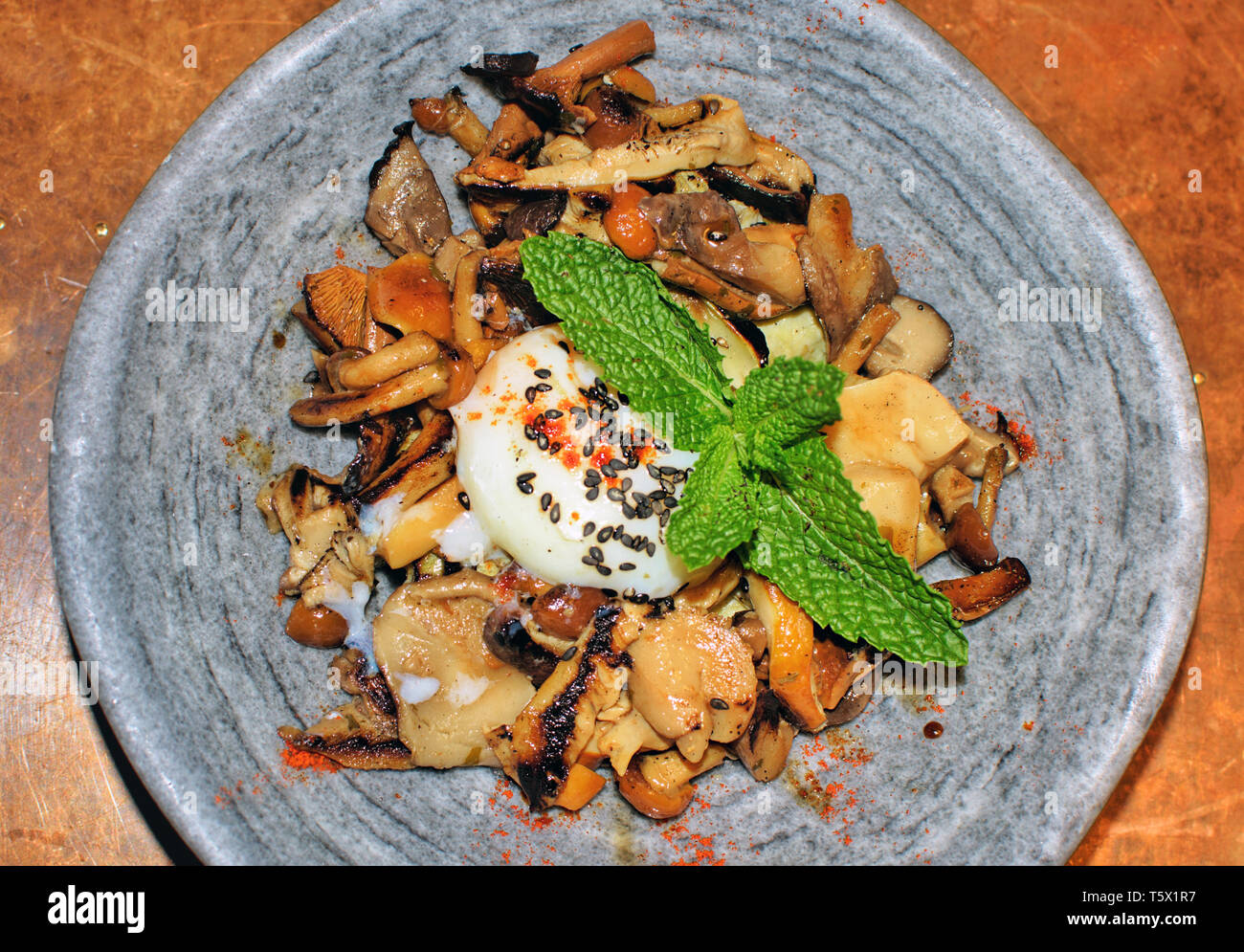 Un bol de champignons et les champignons avec un oeuf cuit à basse température. Cuisine moderne dans l'Espagne en 2019. Oeufs de faible revenu avec champignons, toadstool servi avec une feuille de menthe. Banque D'Images