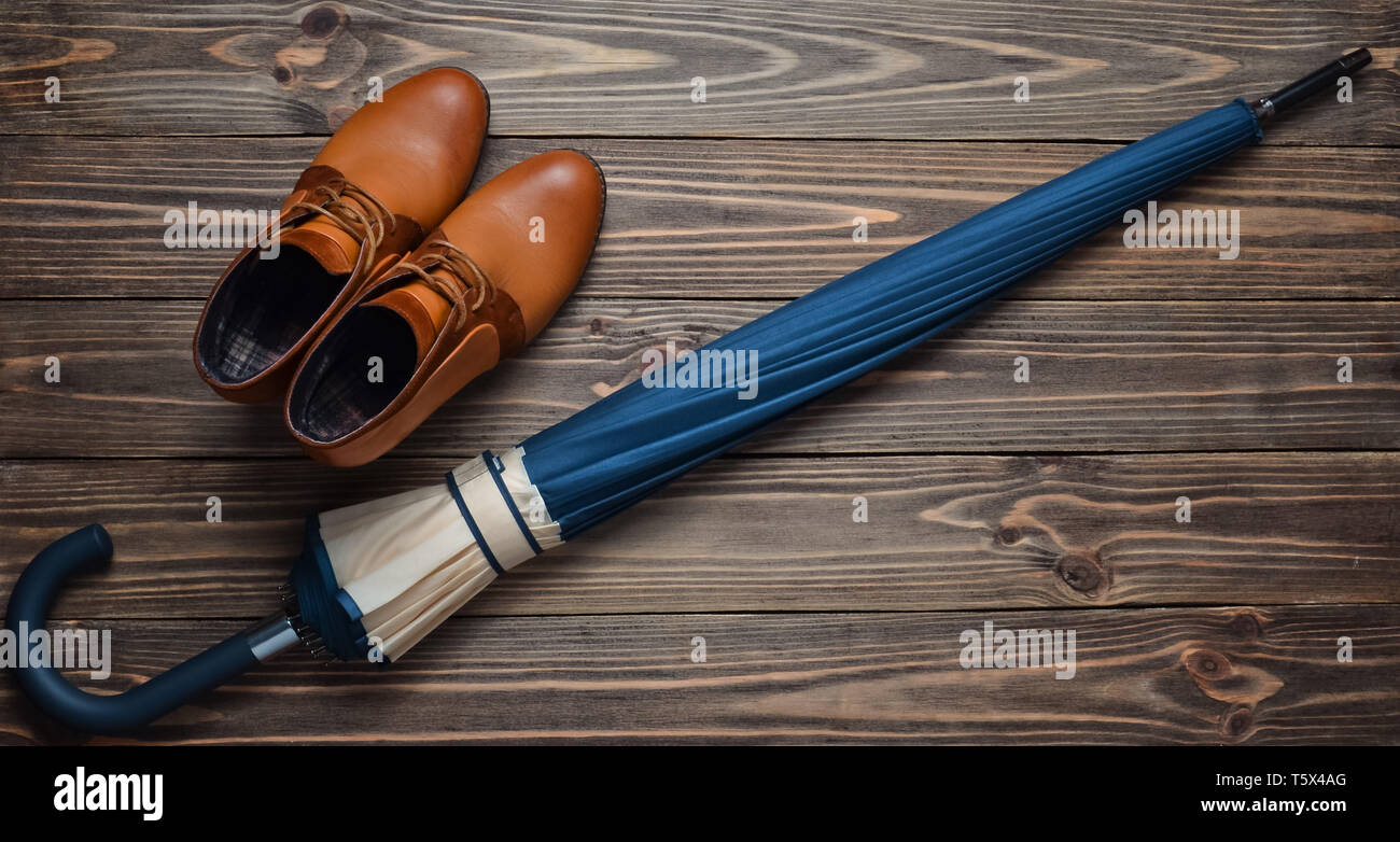 Demi-saison Demi-bottes en cuir et un parapluie plié sur un plancher en bois. Vue d'en haut. Cirer des accessoires féminins pour un temps pluvieux. Banque D'Images