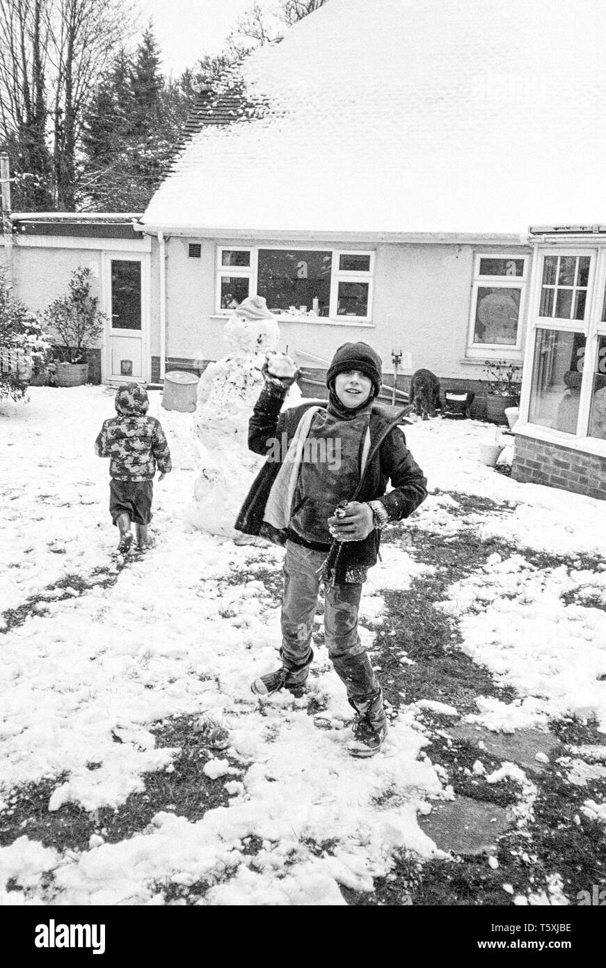 Neuf ans de lancer une balle de neige à l'appareil photo, Medstead, Hampshire, Angleterre, Royaume-Uni. Banque D'Images