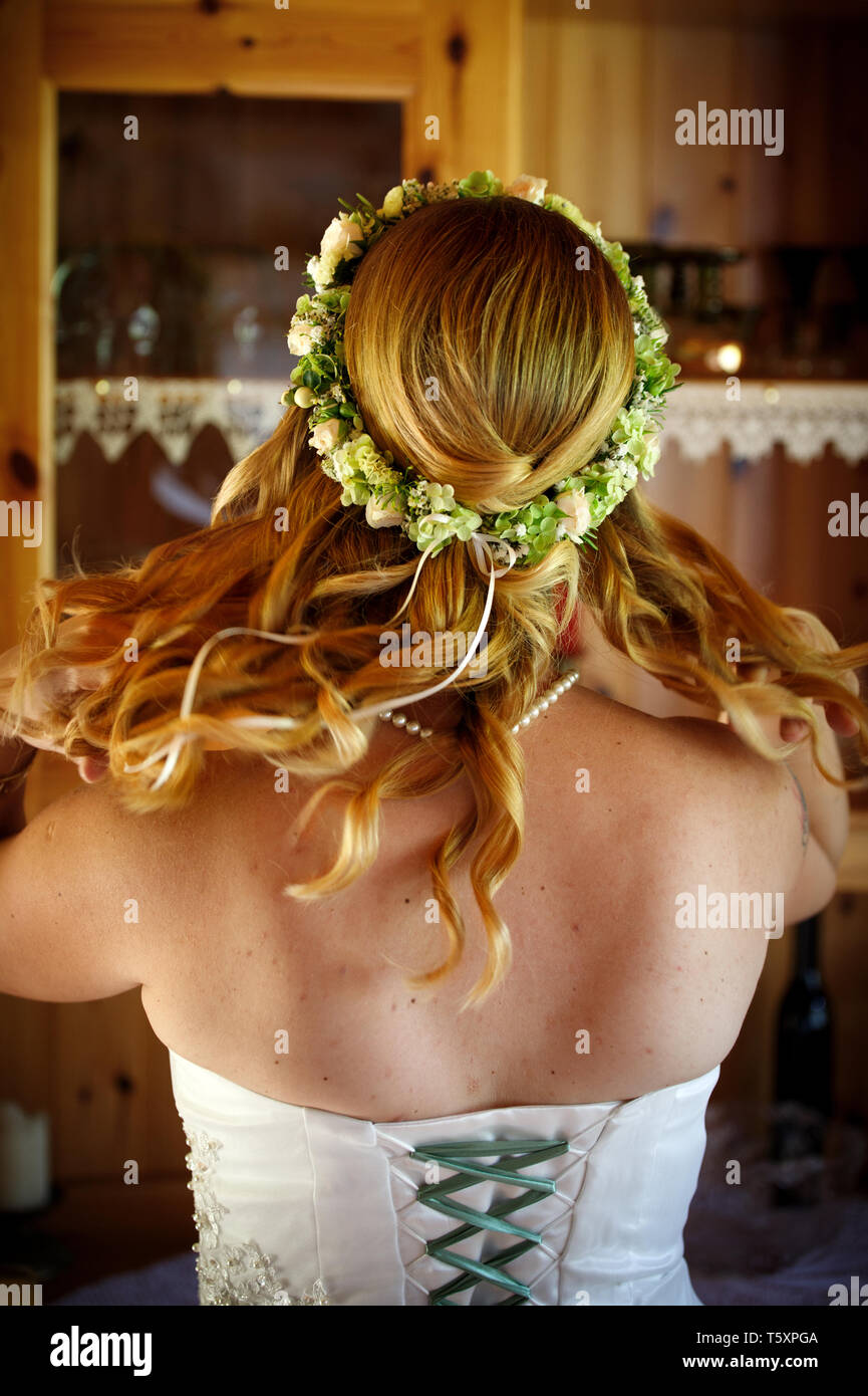 Jeune belle mariée en souriant avec des fleurs dans ses cheveux en jouant avec robe de mariage cheveux sauvages Banque D'Images