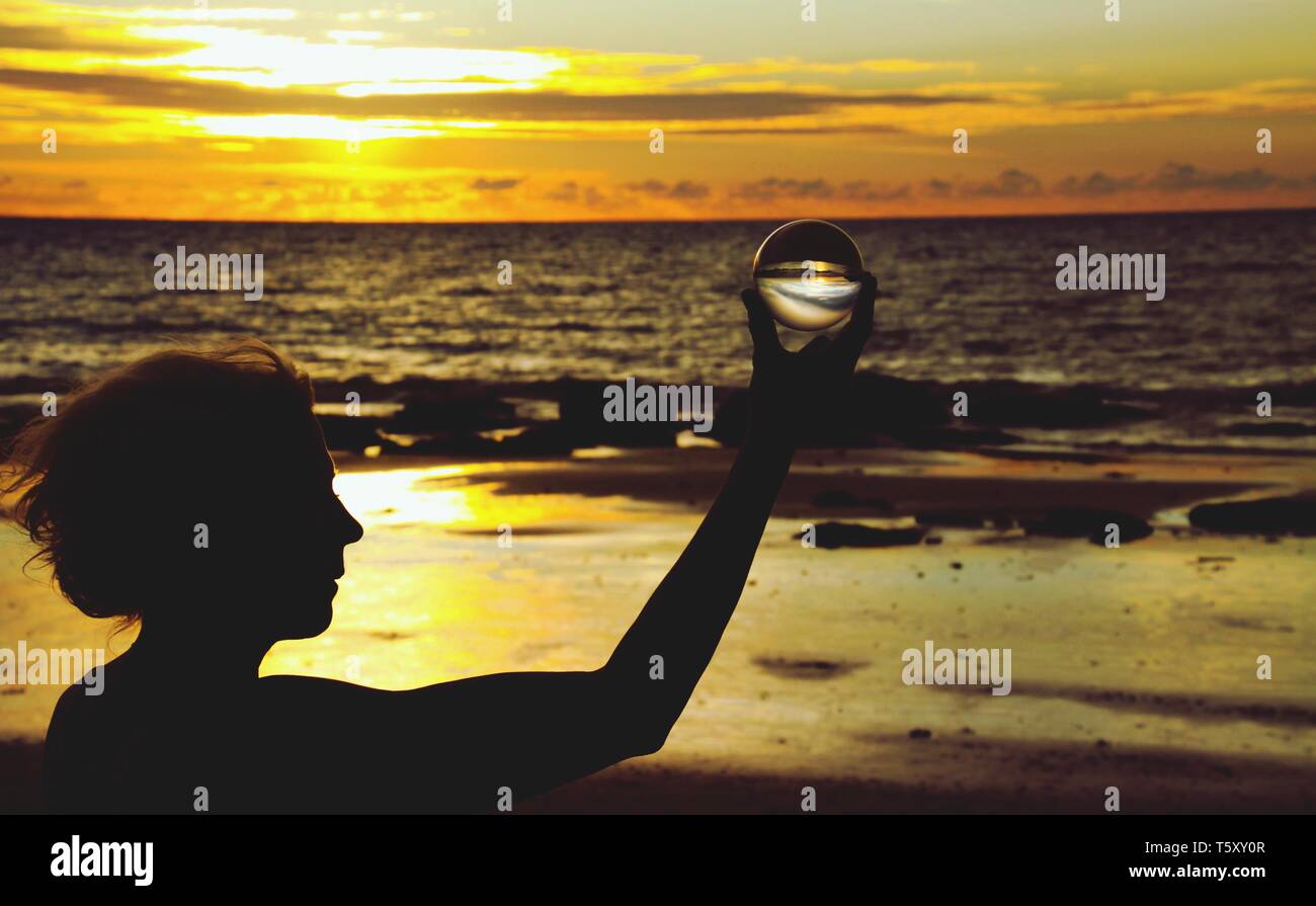 Silhouette de femme tenant une boule de cristal en beau coucher de soleil sur Ko Lanta, Thaïlande Banque D'Images