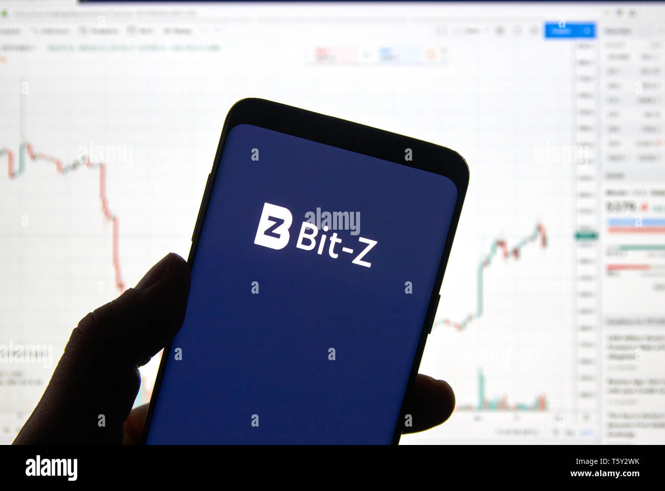 Montréal, Canada - le 26 avril 2019 : Le BIT-Z cryptocurrency logo change et l'application sur Android Samsung Galaxy S9 Plus dans la main sur un ordinateur portable Banque D'Images