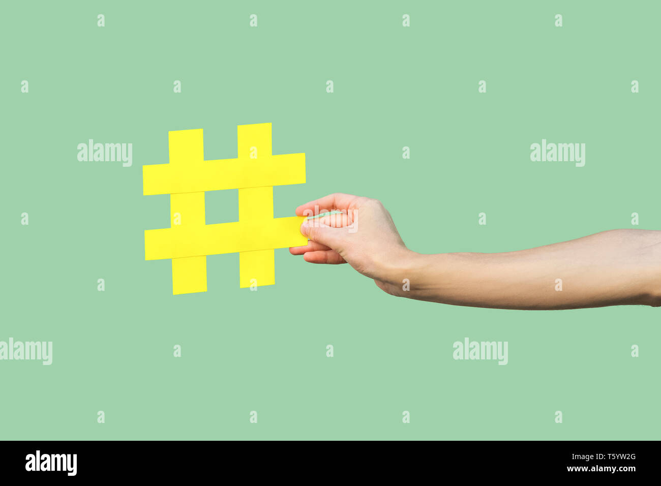 Social media concept, closeup portrait of hand holding large big yellow hash tag signe. Piscine, isolée, copy space, fond vert, marketing symbo Banque D'Images