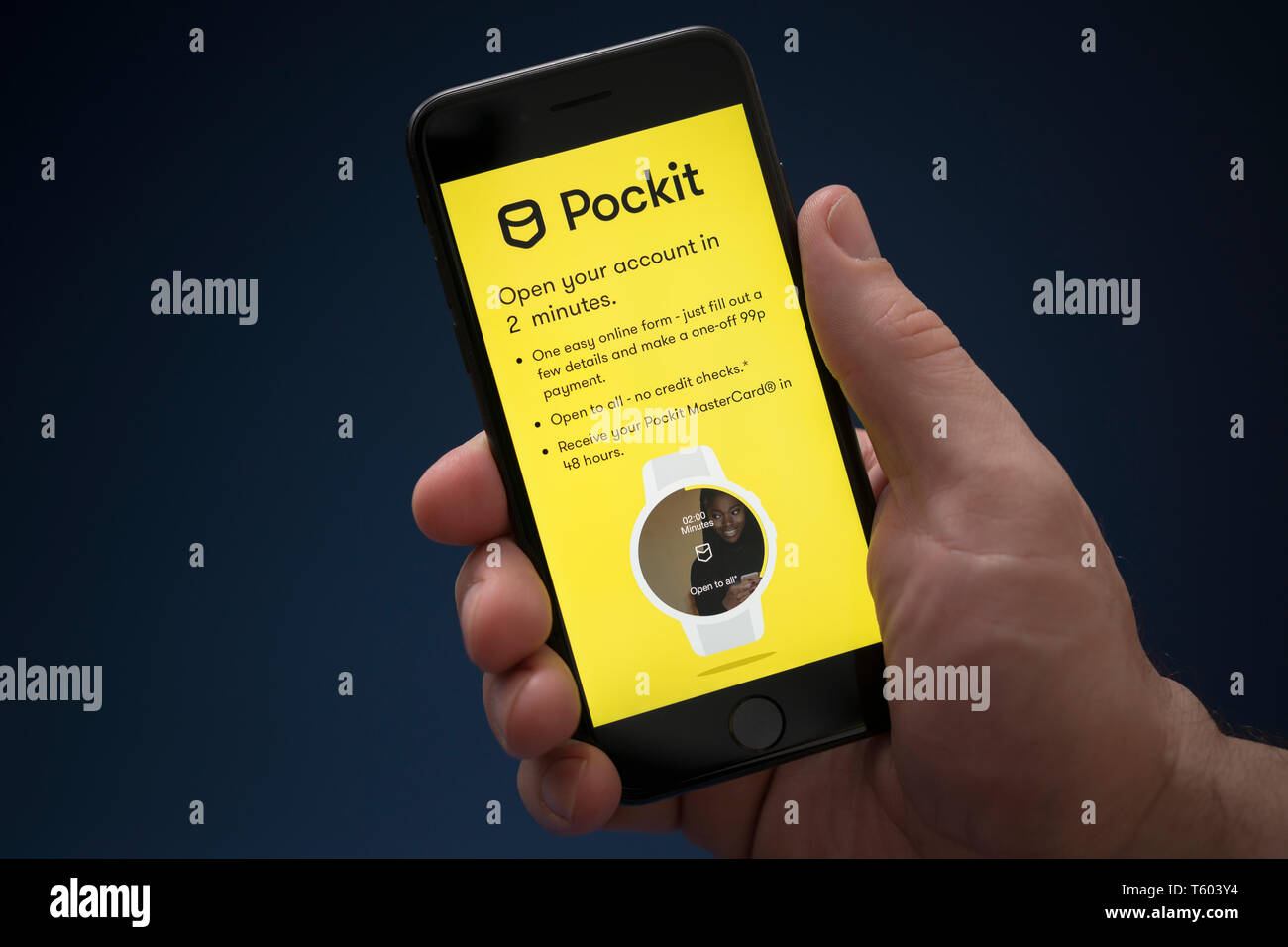 Un homme se penche sur son iPhone qui affiche le logo Pockit (usage éditorial uniquement). Banque D'Images