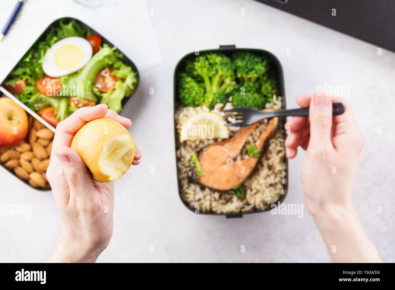 Déjeuner au milieu de bureau en bonne santé. Man eating nutrition le déjeuner de boîte à lunch à emporter à la table de travail avec ordinateur portable. Focus sélectif. Banque D'Images