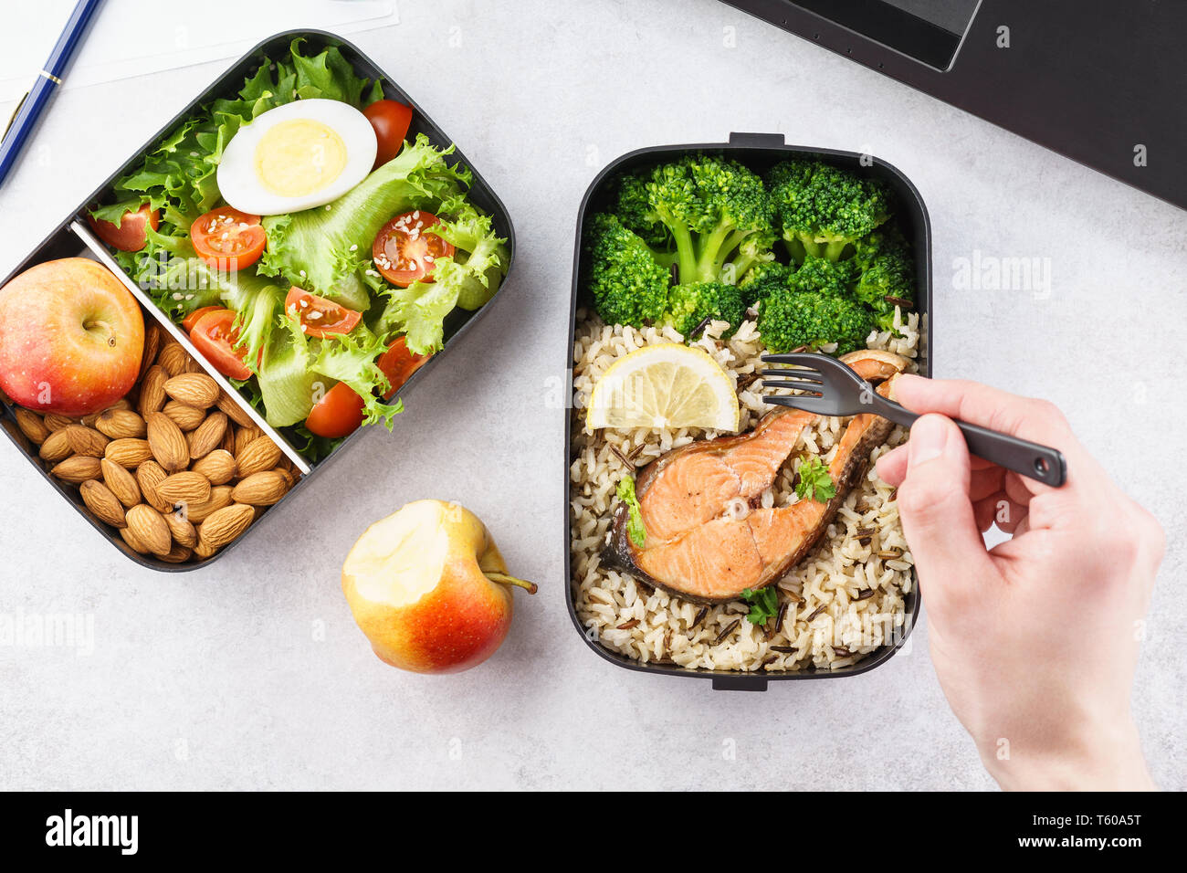 Déjeuner au milieu de bureau en bonne santé. Man eating nutrition le déjeuner de boîte à lunch à emporter à la table de travail avec ordinateur portable. Banque D'Images