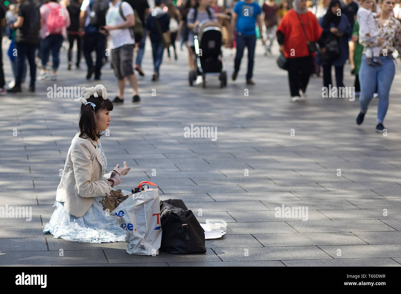 Madame asiatique assis avec un ours en peluche sur sa tête la mendicité à Londres Banque D'Images
