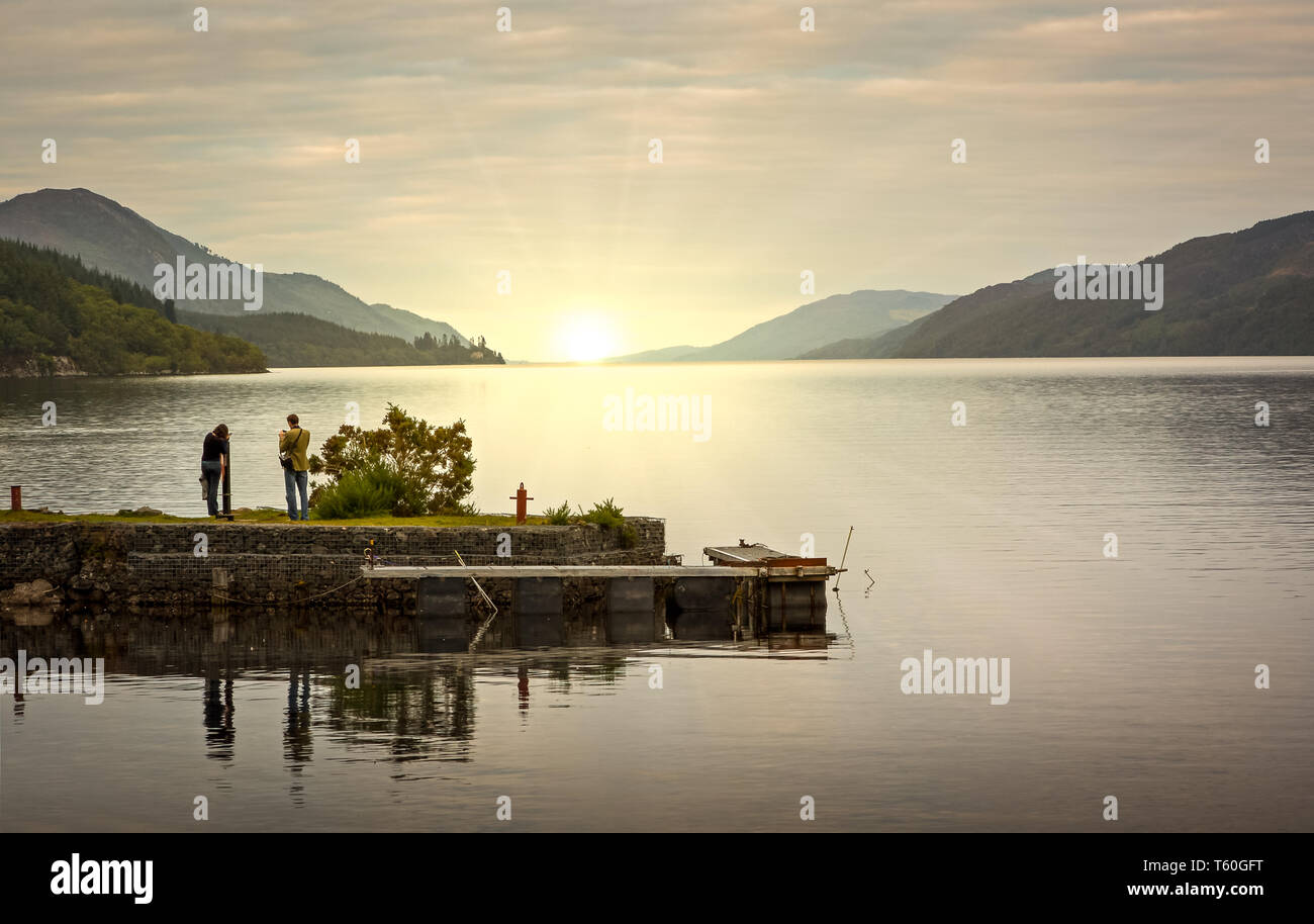 Le Loch Ness lever du soleil photographié à partir de Fort Augustus comme un jeune couple est apparu au bon moment pour apprécier la même vue à couper le souffle. Banque D'Images