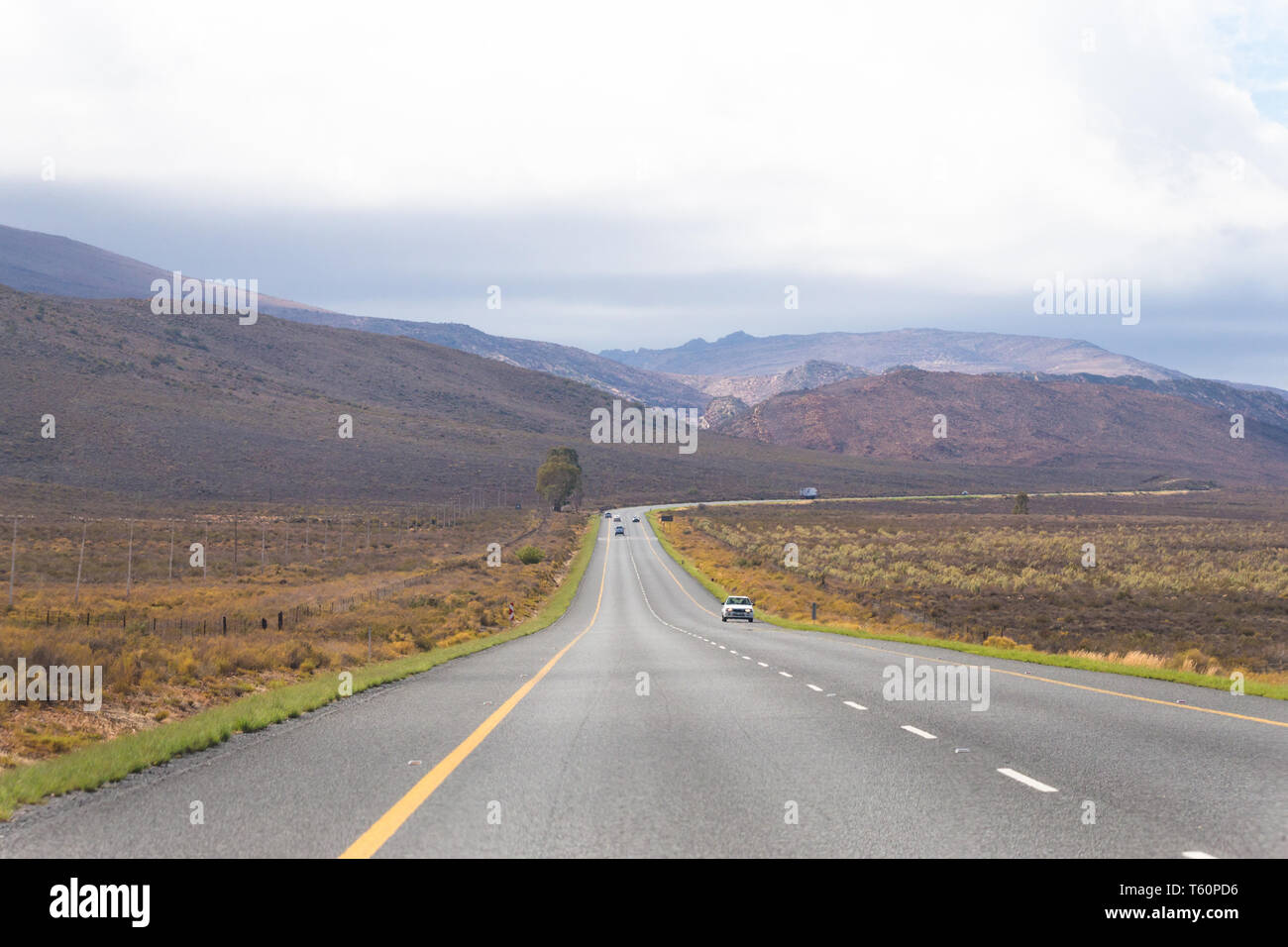 Longue route goudronnée qui s'étend dans la distance du semi aride région désertique de la Karoo en Afrique du Sud sur un fond gris et nuageux ou d'automne journée d'automne Banque D'Images