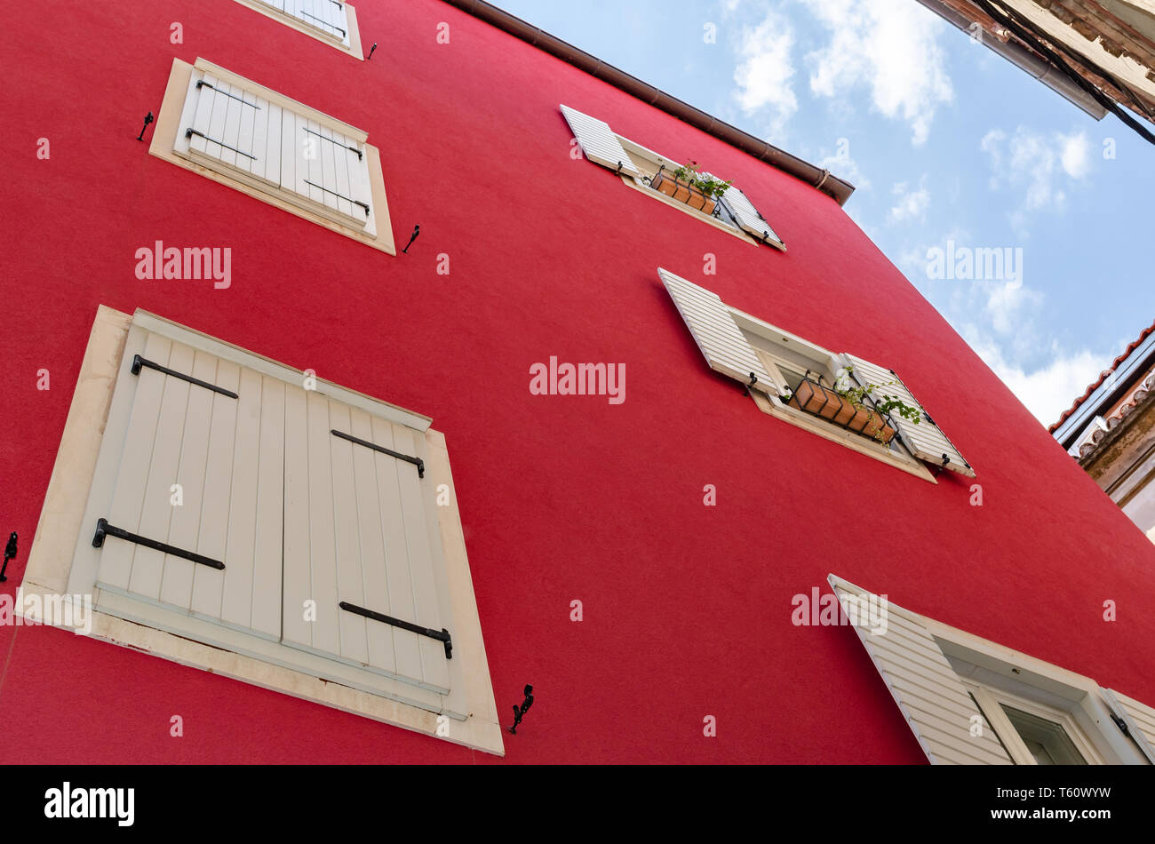 Le mur de la maison est rouge avec des cadres de fenêtre blanc. Banque D'Images